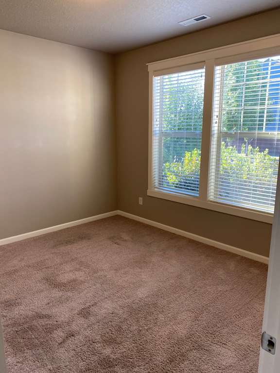 an empty room with two large windows and a carpeted floor