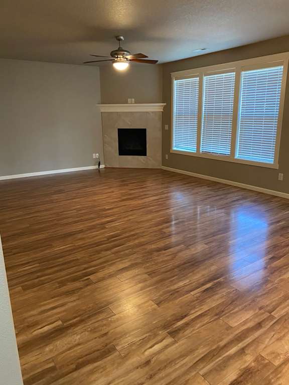 an empty living room with a fireplace and a ceiling fan