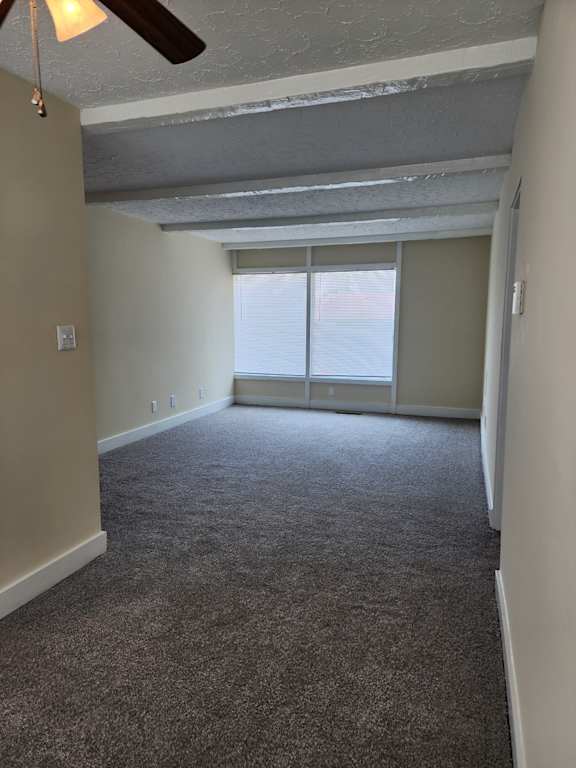 A room with a ceiling fan and carpeted floor.