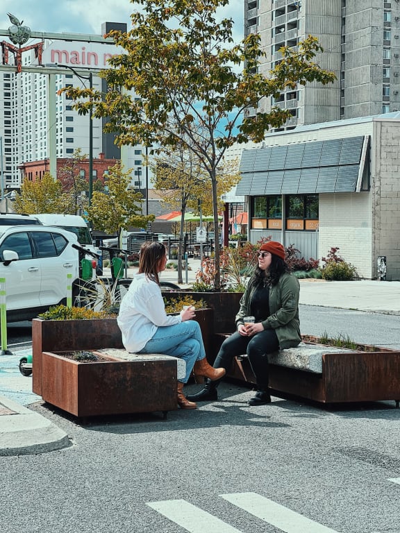 Two Women Sitting on Outdoor Benches in City