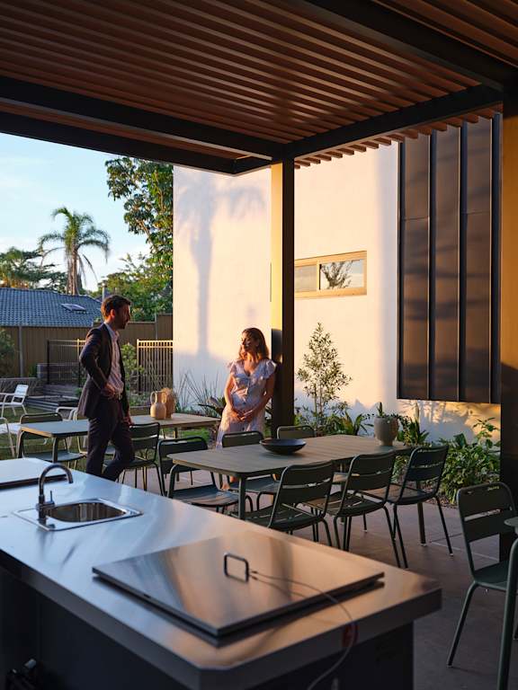 a couple standing on a patio with tables and chairs