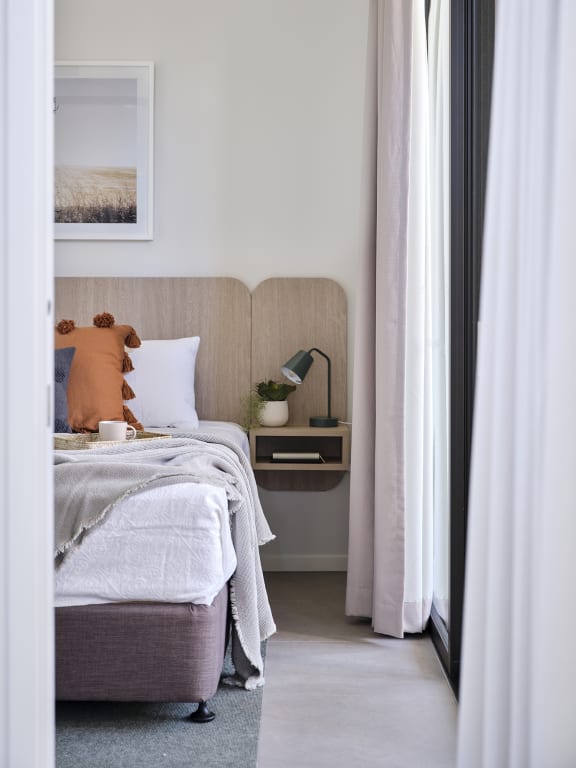 a bedroom with a bed and a nightstand with a lamp and a window