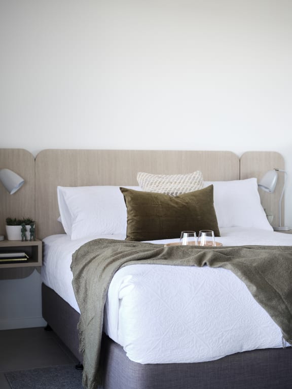 a bed with white sheets and brown pillows and a blanket