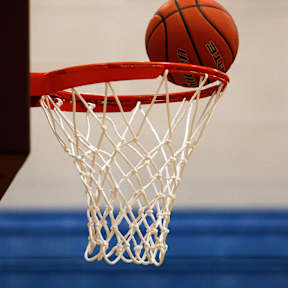A basketball is about to go through the net.