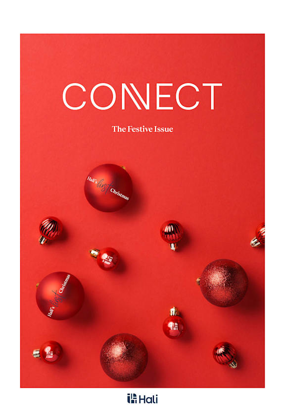 A red cover of a magazine with Christmas ornaments scattered on it.