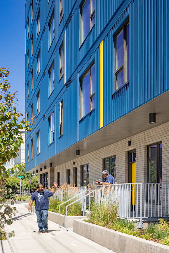 people walking down a sidewalk in front of a blue building