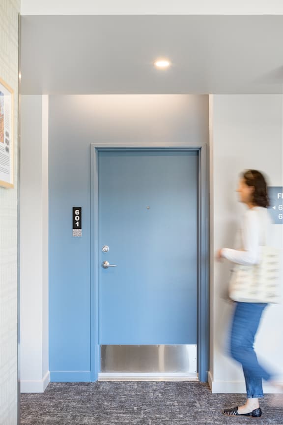 a woman walking out of a room with a blue door