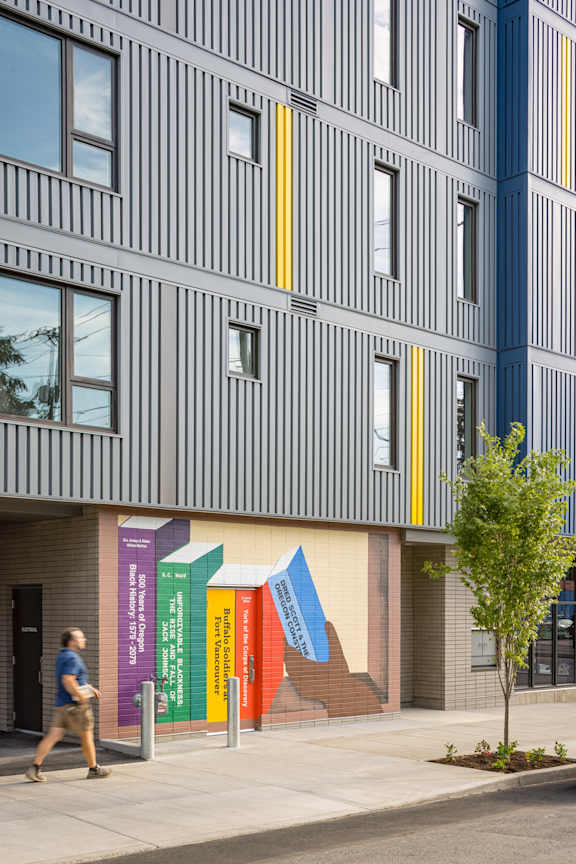 a building with colorful doors and a person walking on the sidewalk