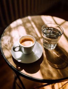 A cup of coffee and a glass of water are placed on a table.