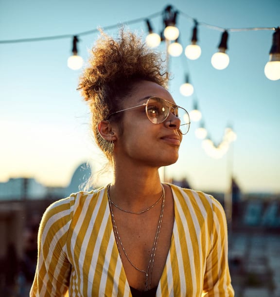 a woman in a yellow and white striped shirt and sunglasses holding a soda