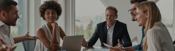 a group of people sitting around a table with a laptop