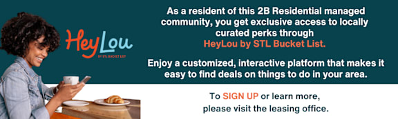 A woman is sitting at a table looking at her phone with a Heylou logo in the background.