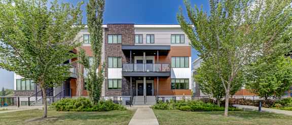 A modern multi-story apartment building with a balcony on the second floor.