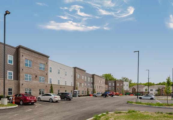 A street view of a residential area with apartment buildings and cars parked on the side of the road.