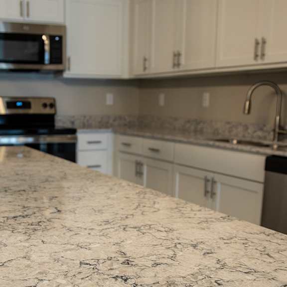 A kitchen with a granite countertop and white cabinets.