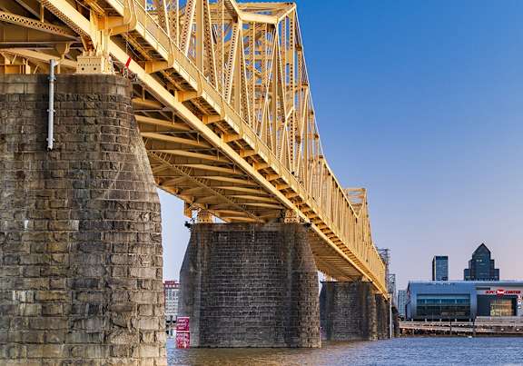 A bridge over a river with a city skyline in the background.
