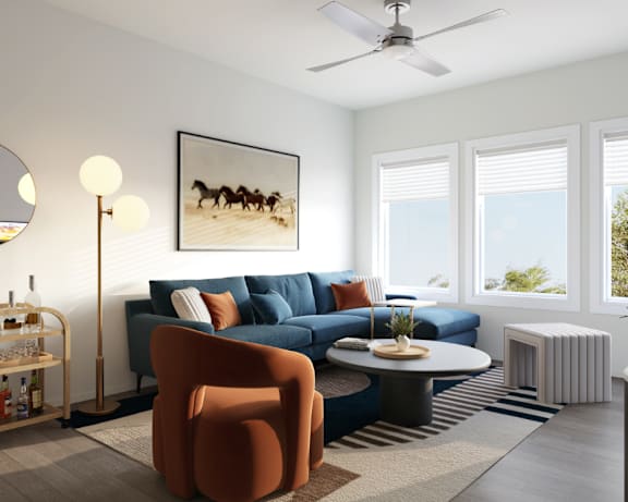 A living room with a blue couch and a round mirror on the wall.