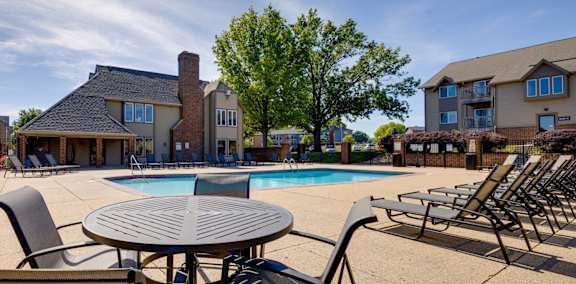 A sparkling outdoor pool with clear blue water and sun loungers offers a relaxing space for residents to swim and unwind.