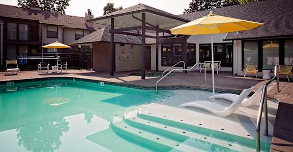 A yellow umbrella is next to a pool.