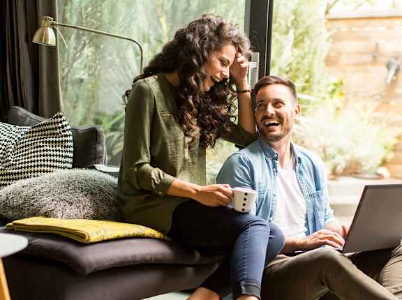 a man and woman sitting on a couch with a laptop