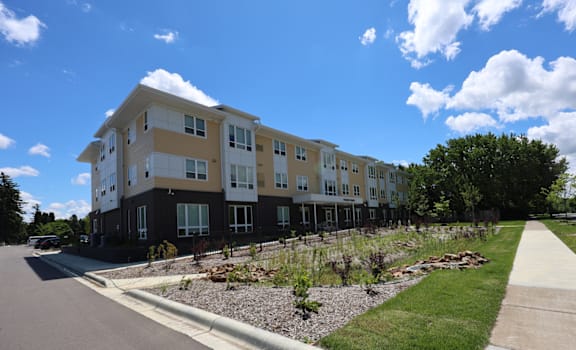 A modern apartment building with a well-maintained lawn in front.