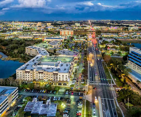 an aerial view of a city at night with a ferris wheel in the background at The Rialto, Orlando, FL