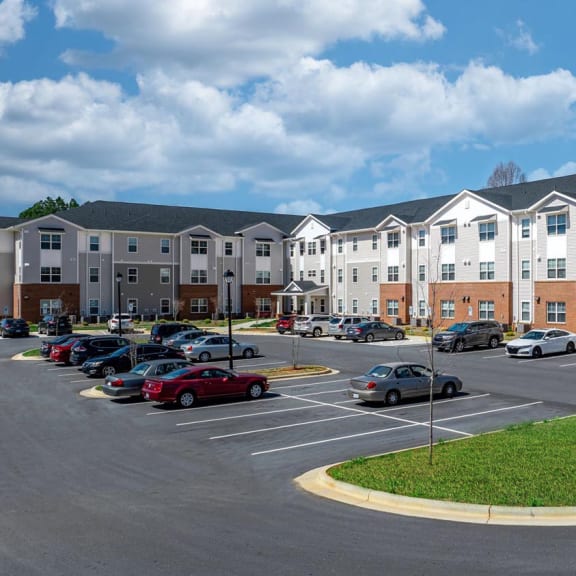 a parking lot with cars in front of an apartment building