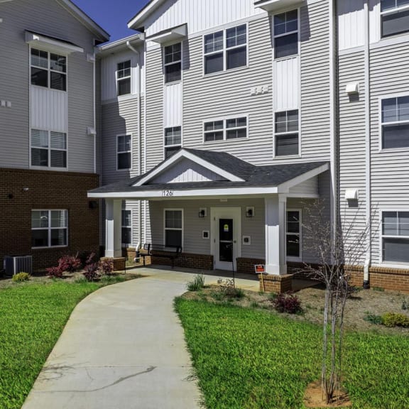 a pathway leading to an apartment building with a porch