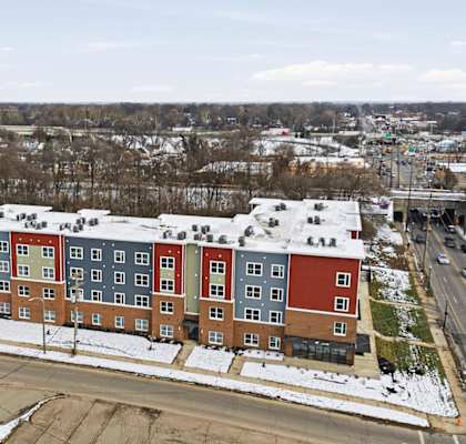 A large multi-story building with red and blue sections is surrounded by snow.