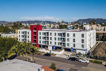 A red and white building is in the foreground with cars parked in front.