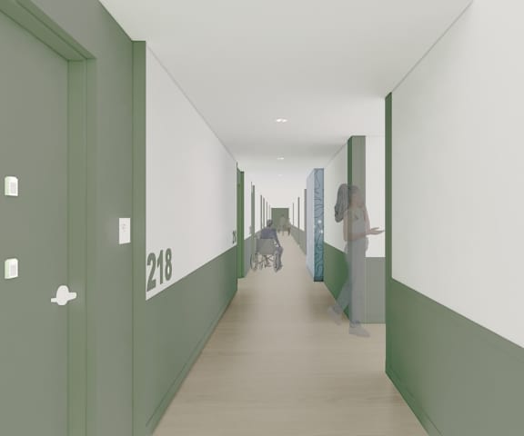 A long hallway with doors on the left and a person walking down the hall.