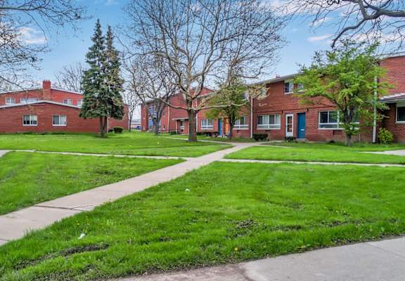 A row of red brick houses with green lawns in front.