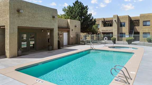 A swimming pool in front of a building with a fence around it.