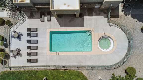 A swimming pool with a hot tub in the middle of a backyard.