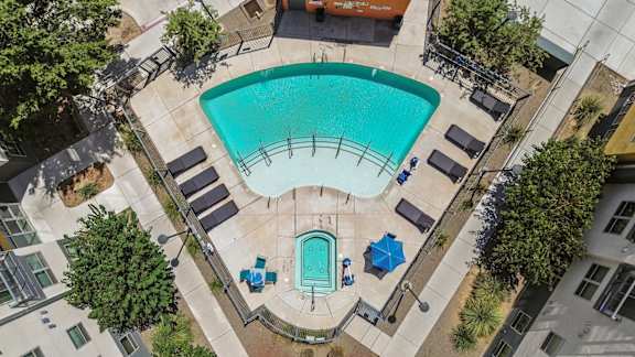 A swimming pool surrounded by lounge chairs and trees.