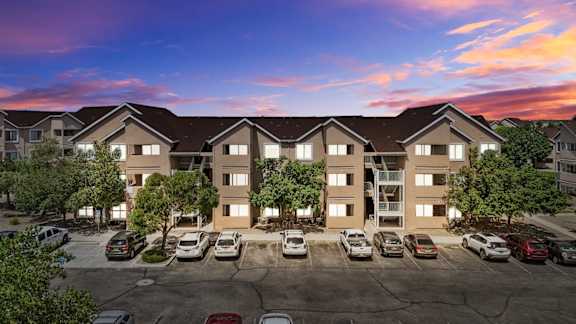 A large apartment complex with a parking lot in front.