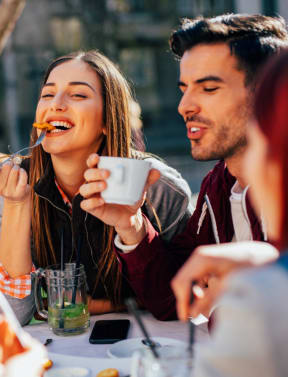 group of people sitting around a table eating food and drinking