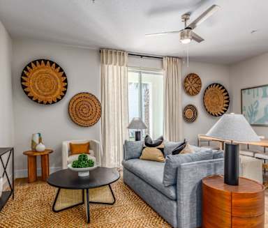 A living room with a grey couch, a round table, and a painting on the wall.