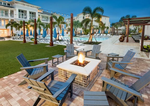 a patio with a firepit and chairs and a pool in the background