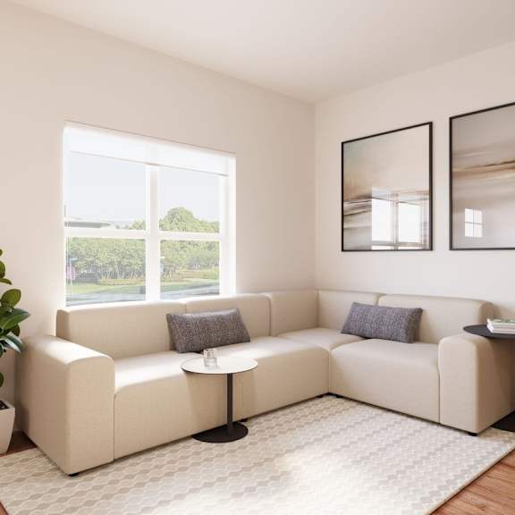 A living room with a white couch, a small table, and a potted plant.at The Landing at Hub City, Wisconsin