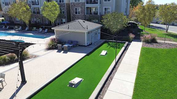 Aerial view of property showing outdoor entertaining areas including pool, gas grills, fire pit, cornhole and fountain