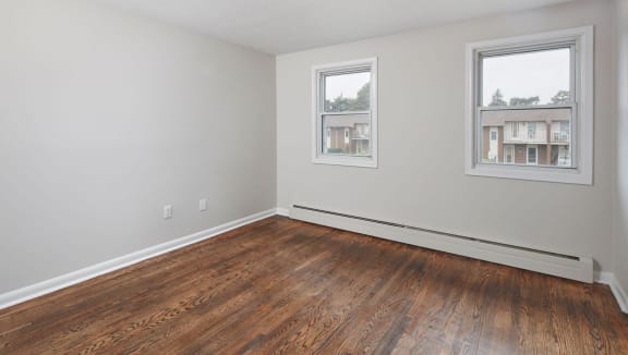 Bright bedroom with two windows and medium vinyl plank flooring.