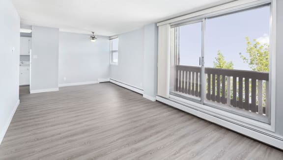 view of empty living room, dining room and balcony with vinyl plank flooring.