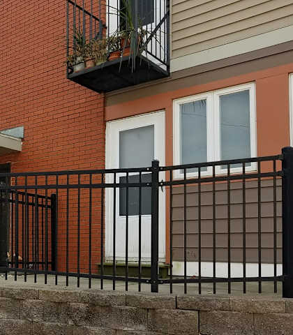A red brick house with a black iron fence.