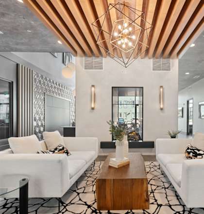 A modern living room with white furniture and a wooden ceiling light fixture.