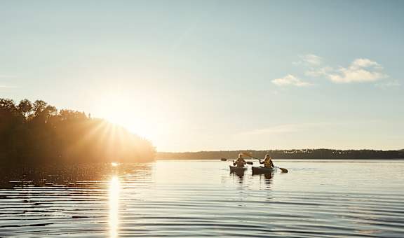 Two people are kayaking on a calm lake at sunset at The Bosk Apartment Homes, Woodbury, Minnesota