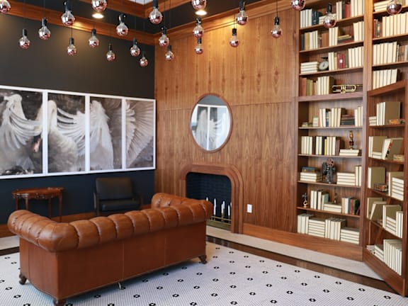 A room with a fireplace, bookshelves, and a leather couch.