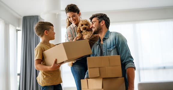 A family is moving into a new home with boxes and a dog.