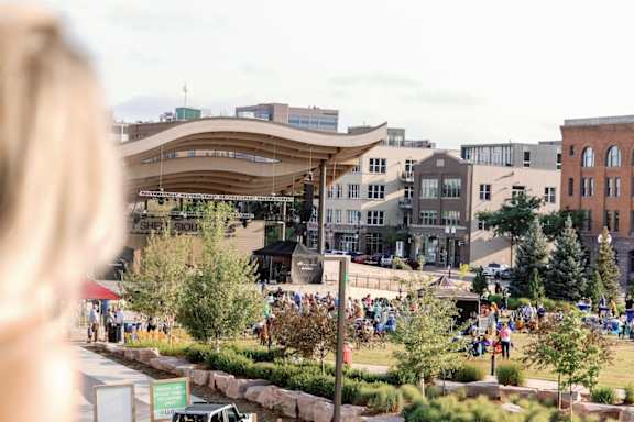 A woman with blonde hair is looking at a park with people walking around.