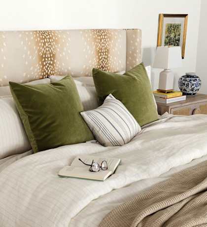 A bed with a white comforter and a decorative headboard with a pattern of dots.